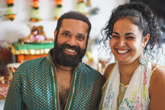 Indian husband and wife smiling in front of the camera - Portrait of happy southern asian couple - Love, ethnic and india's culture concept - Focus on woman face