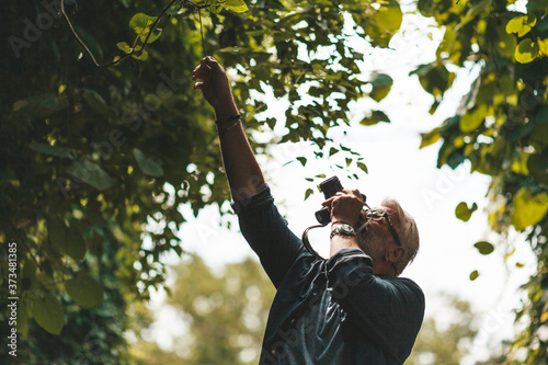 Fotografía An elderly naturalist is studying the flora in the forest, taking pictures