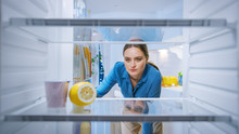 Dissappointed And Angry Young Woman Looks Inside The Fridge, Checks Out That It's Empy. Point Of View POV From Inside Of The Kitchen Refrigerator