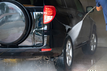 Car washing. Cleaning car with high pressure water and foam