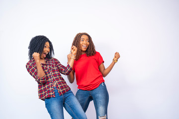 Wall Mural - two beautiful young black women feeling excited and celebrating, facing the space to their side