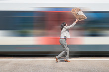 Woman On A Railroad Station Platform And Her Business Newspaper Flying Away When An Incoming Train Passing By In Switzerland.