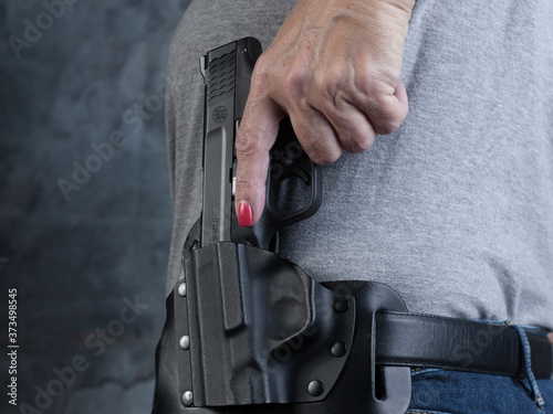 Women\'s hand holstering a gun close up