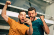 Two happy excited fan friends in euphoria mood after winning in a bet with a smartphone in hand on stadion background