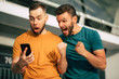 © My Ocean studio - Two happy excited fan friends in euphoria mood after winning in a bet with a smartphone in hand on stadion background