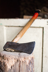 Wall Mural - Closeup shot of an ax put on the stump and a white wooden surface