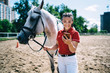 Horsewoman with smartphone walking stallion