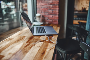 A laptop for remotely smart working by the window in a coffee shop. Cozy workplace