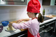 © Cavan Images - Girl with red chef's hat makes pizza dough with a rolling pin