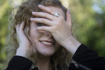 Sticker - Closeup shot of a beautiful blonde female smiling and covering the half of her face with her hand