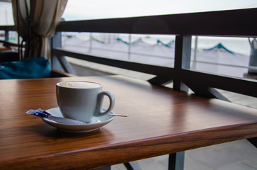 White cup of cappuccino on wooden table in cafe