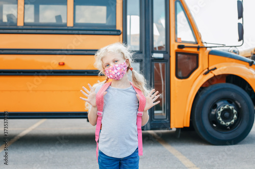 Cuadros en Lienzo Happy Caucasian girl student wearing face mask near yellow bus