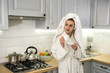 © RomanR - Happy pretty young woman before workday enjoys coffee on the kitchen  after shower in bathrobe
