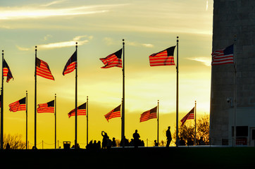 Washington Monument and silhouettes and waving national flags during sunset - Washington D.C. United States of America