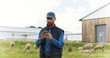 © VAKSMANV - Handsome male Caucasian hands holding and texing message on smartpphone outdoors. Sheep at grazing pasture on background. Man shepherd tapping and scrolling on mobile phone. Cattle farm.
