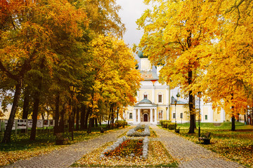 Ancient christian church and autumn yellow trees. Beautiful domes, high old bell tower against the sky