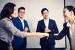 © PRASERT - Business people shaking hands, between meeting in seminar room