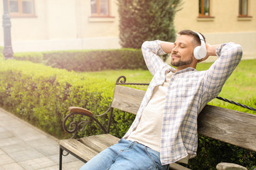 Wall Mural - Handsome man listening to music while relaxing in park