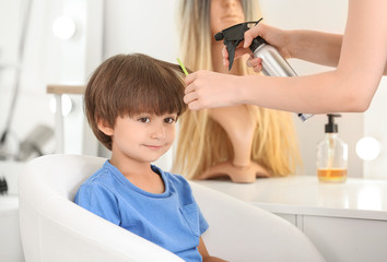 Wall Mural - Female hairdresser working with little boy in salon