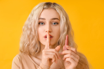 Canvas Print - Beautiful young woman with lipstick showing silence gesture on color background