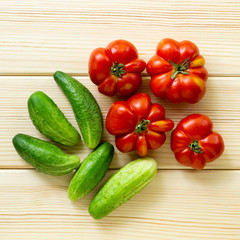 Wall Mural - Ripe tomatoes and cucumbers on a light wooden background, top view