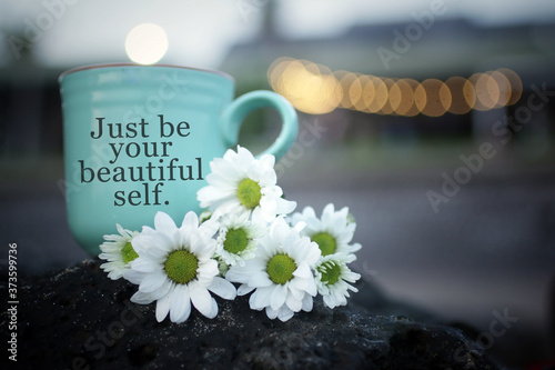 Inspirational motivational quote - Just be your beautiful self. With cup of coffee or tea with flowers on sea rock and the light bokeh background. Love and believe in yourself concept. Spa still life.