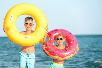 Poster - Cute children with inflatable rings on sea beach at resort