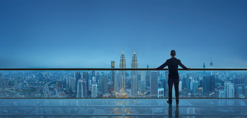 businessman standing on open roof top balcony watching city night view . business ambition and visio
