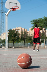 Poster - Vertical shot of a ball in a basketball court with a man on the background