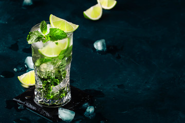 Canvas Print - Mojito cocktail or mocktail with lime, mint, and ice in glass on blue background. Summer cold alcoholic non-alcoholic drink,  beverage and cocktail. Copy space