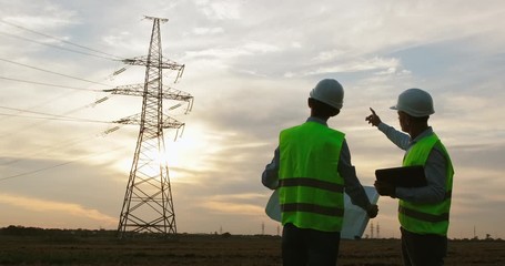 Wall Mural - engineers in special clothes discuss upgrading a high-voltage power line using a paper plan and a ta
