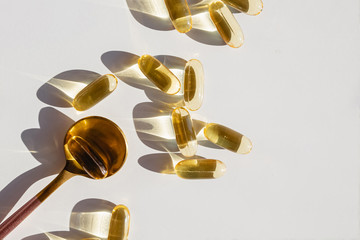 Omega 3 capsules in the spoon on white table.