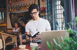 © BullRun - Focused male reading notebook sitting in cafeteria with laptop