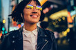 © BullRun - Cheerful woman teenager in glasses with neon lights spending evening in megalopolis and relaxing with positive music,youthful hipster girl in electronic headphones listening audio playlist in New York