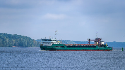 Wall Mural - Laden general cargo ship sailing along coastline from Vyborg port to Gulf of Finland.