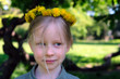 Little blonde smiling girl with a dandelion wreath on head