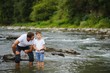 © Serhii - A father teaching his son how to fish on a river outside in summer sunshine. father's day.