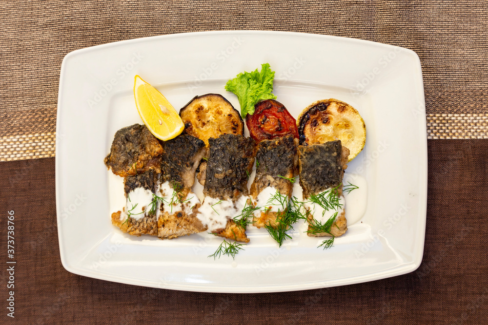 Pieces of fried fish fillet with grilled vegetables (zucchini, tomato ...