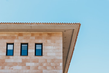 Low angle shot of a building in Majorca, blue sky background. Three windows stand out in contrast to the facade