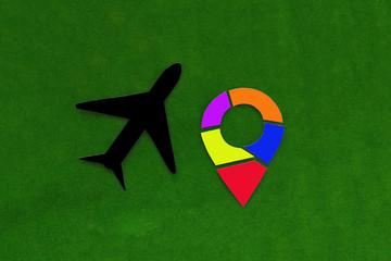 Fototapete - The plane is black, with a multicolored geolocation sign on a green background. Air travel, Travel, tourism.