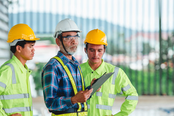 A team of three Asian construction engineers and architects Wear safety clothing and helmet. Jointly think and work in construction design