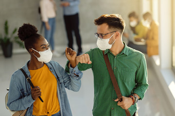 Poster - Happy college friends with face masks elbow bumping in a hallway.