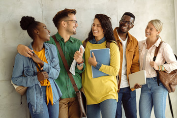 Wall Mural - Group of happy college friends talking in a hallway.