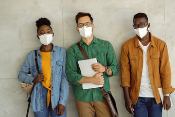 Canvas Print - Happy students with face masks by the wall at university hallway.