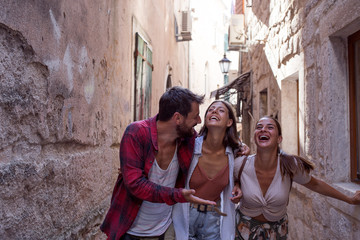 Group of excited friends walking on streets and smiling