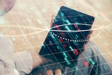 Double exposure of man's hands holding and using a digital device and forex graph drawing. Financial market concept.