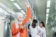 © godji10 - Muslim woman wearing hijab playing with tablet on her way to work. Business people, Company staff, workers using cellular in a subway train. Concept of 5G communication technology, internet networks