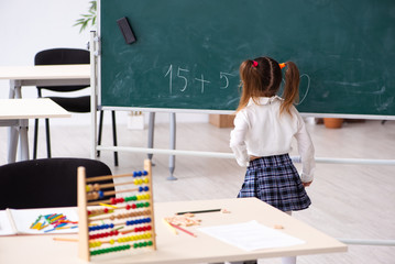 Small girl in front of blackboard in the classroom