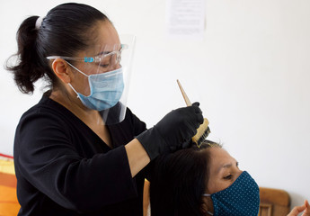 Hairdresser wearing a mask doing her client's hair