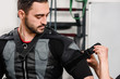 Closeup of coach dressing man in electro muscular stimulation vest